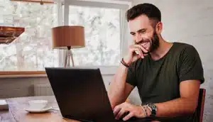 Webinar-Aufzeichnungen - Mann sitzt lächelnd vor Laptop